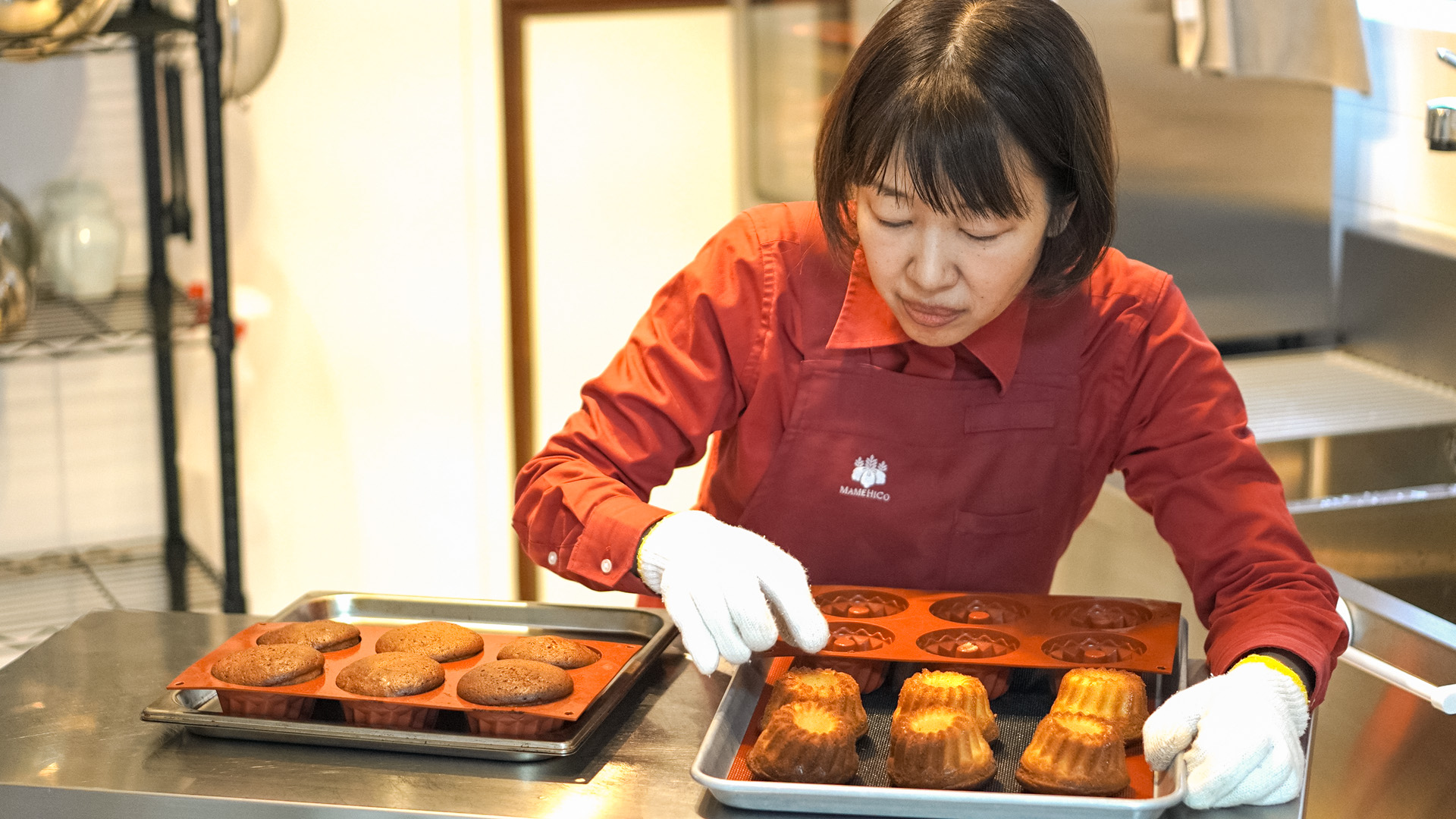 焼き上がったマフィンを型から外すスタッフ