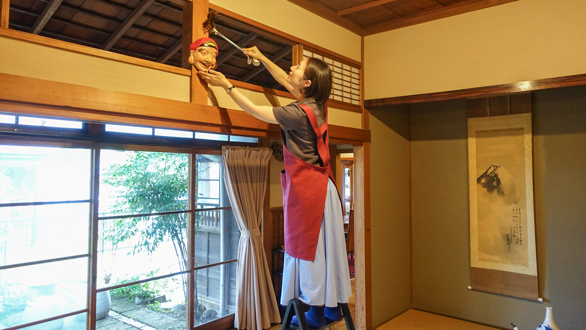 脚立に上って欄間を掃除するスタッフ