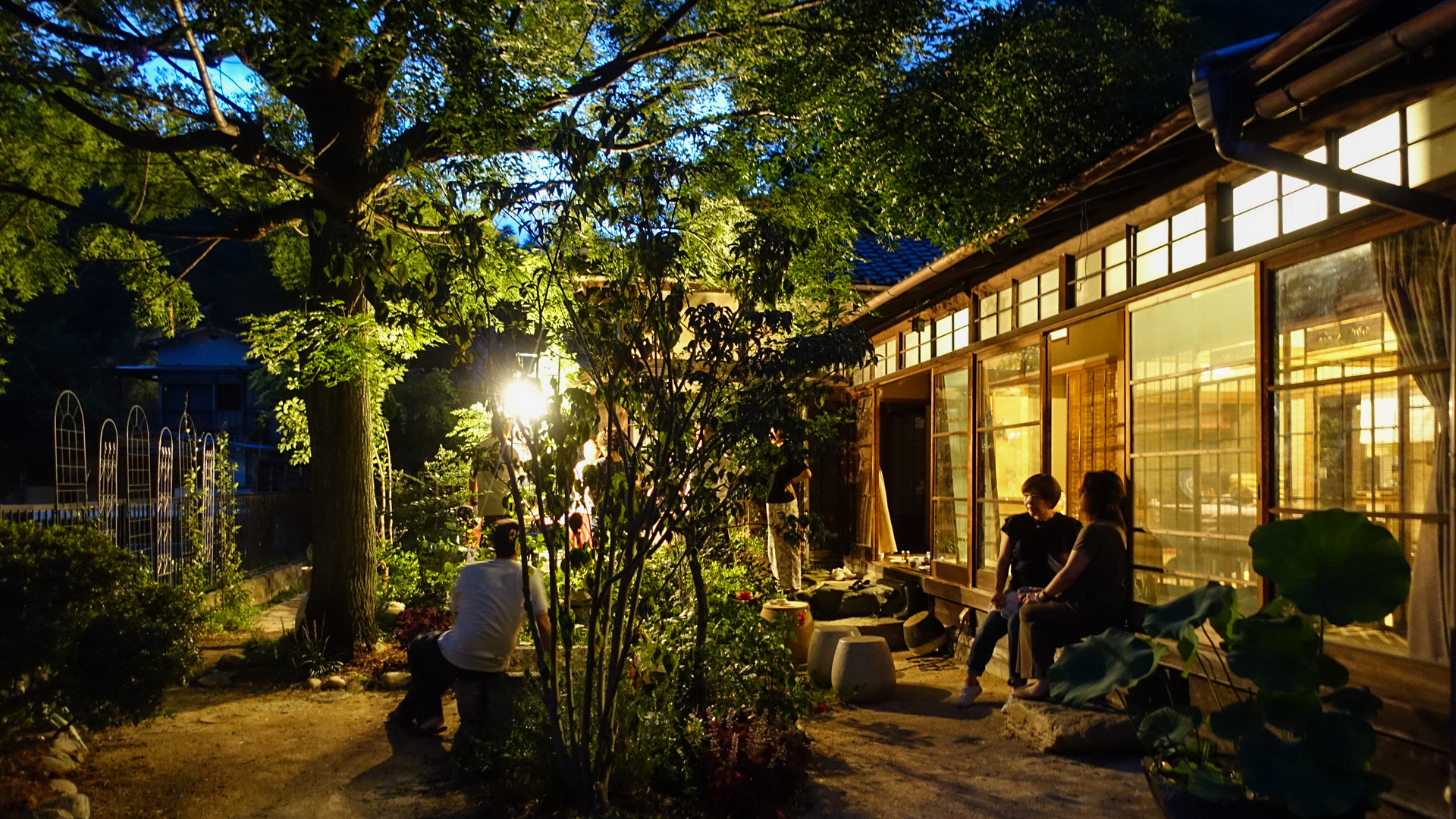 夜、灯りのともった紫香邸の縁側で語らう人たち