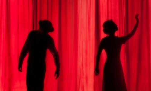 silhouette of three performers on stage