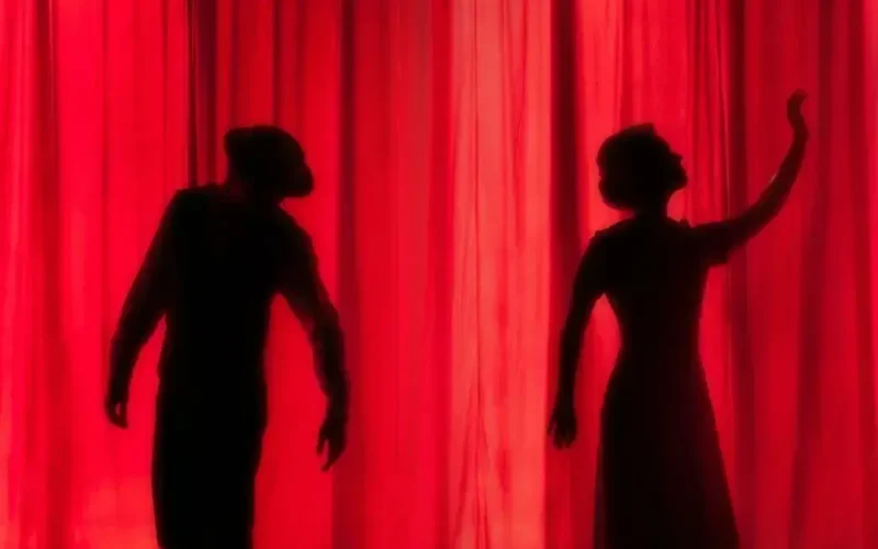 silhouette of three performers on stage